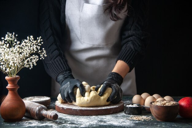 正面図女性料理人が暗いペストリーの仕事で生地をロールアウト生生地ホットケーキパイオーブン