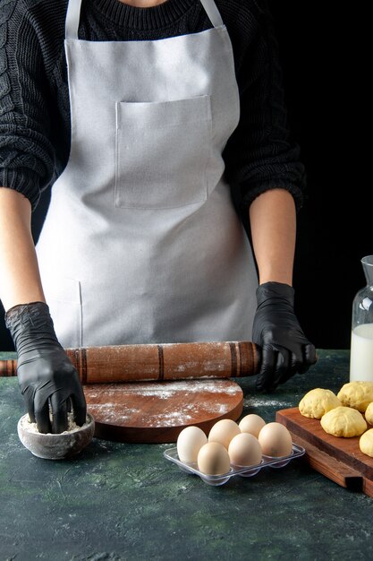 正面図女性料理人が暗い仕事の料理に小麦粉で生地を広げているホットケーキ生生地焼きケーキパイ労働者