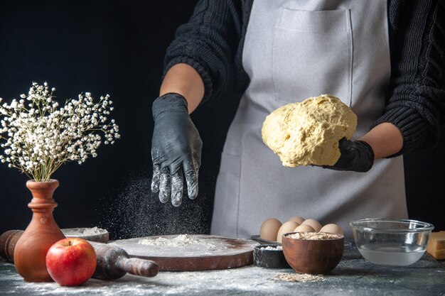 Front view female cook rolling out dough with flour on the dark job dough pastry kitchen hotcake cuisine bakery egg