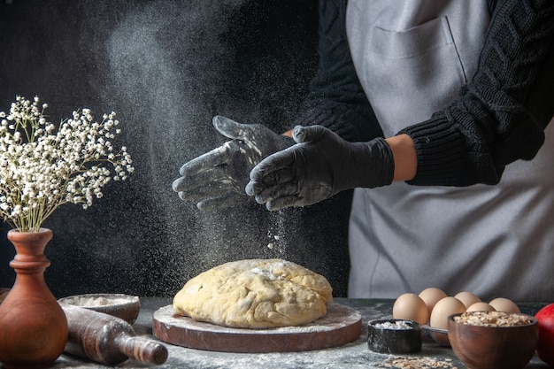 Cuoca di vista frontale che stende la pasta con la farina sul lavoro scuro pasta cruda panetteria torta forno pasticceria hotcakes