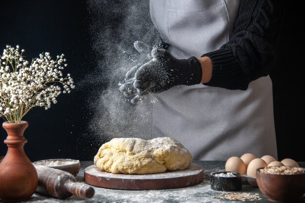 正面図女性料理人が暗い仕事の生の生地のホットケーキベーカリーパイオーブンで小麦粉と生地をロールアウト