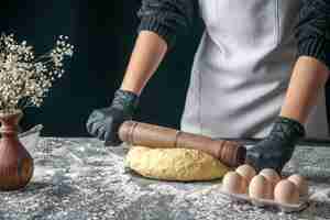 Foto gratuita vista frontale cuoca stendere la pasta con il mattarello sull'impasto scuro uovo lavoro panetteria hotcake pasticceria cucina cucina