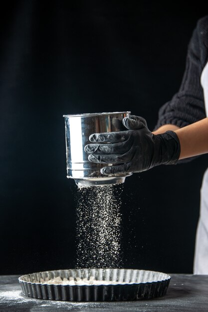 Front view female cook sowing white flour into pan on dark pastry job egg cake pie bakery worker cuisine