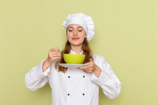 녹색 책상 주방 요리 요리 음식 식사 여성에 접시와 녹색 접시를 들고 흰색 쿡 정장 여성 요리사의 전면보기