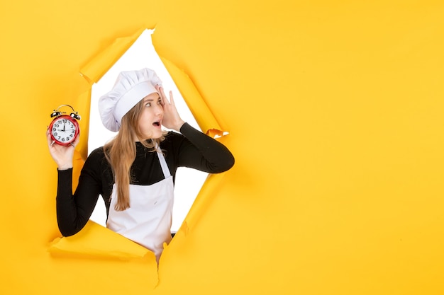 Foto gratuita cuoca vista frontale con orologi sull'ora gialla cibo foto colore lavoro cucina emozione sole cucina