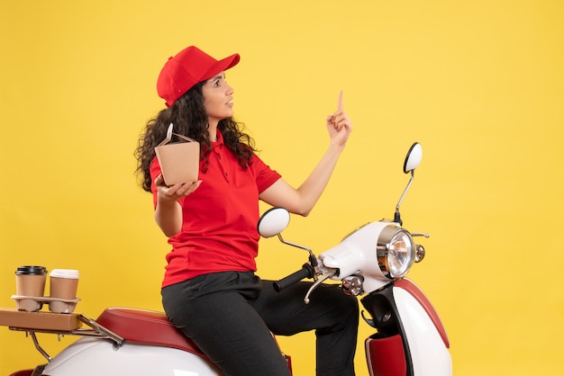 Front view female courier on bike for coffee and food delivery on a yellow background service delivery uniform worker work job woman