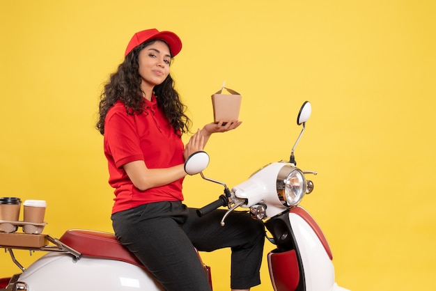 Front view female courier on bike for coffee and food delivery on yellow background service work delivery uniform job woman