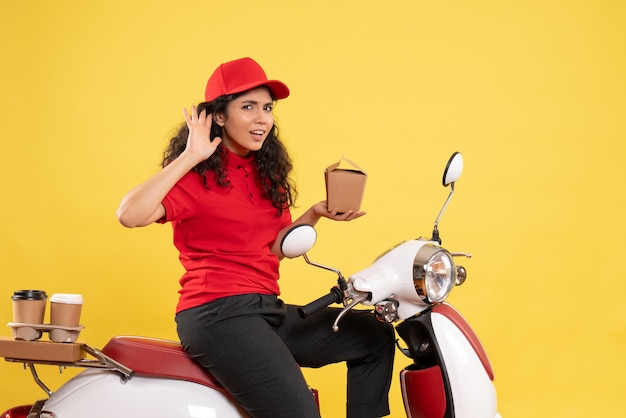 Front view female courier on bike for coffee and food delivery on a yellow background service work delivery uniform worker job woman