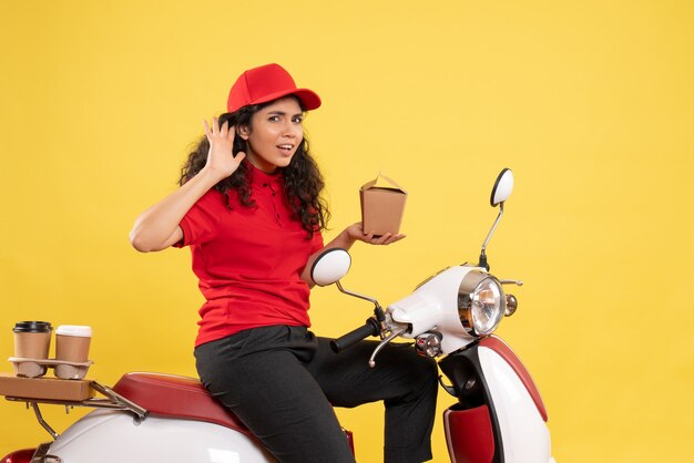 Front view female courier on bike for coffee and food delivery on a yellow background service work delivery uniform worker job woman