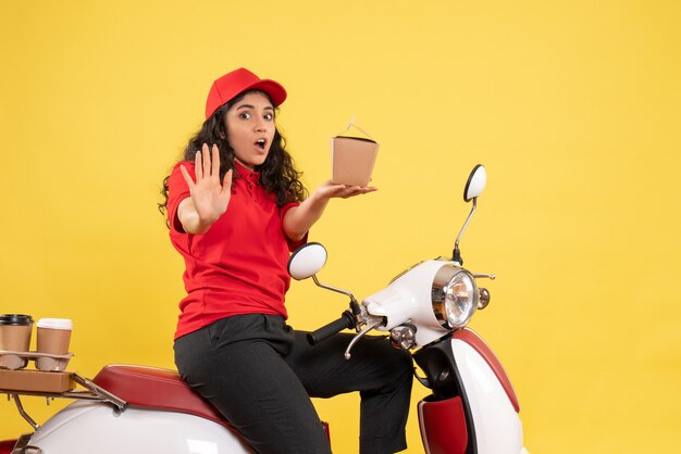 노란색 배경 서비스 작업 배달 유니폼 작업자 여자에 커피와 음식 배달을위한 자전거에 전면보기 여성 택배