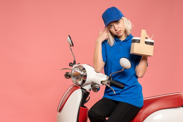 Front view female courier on bike with coffee cups on pink 