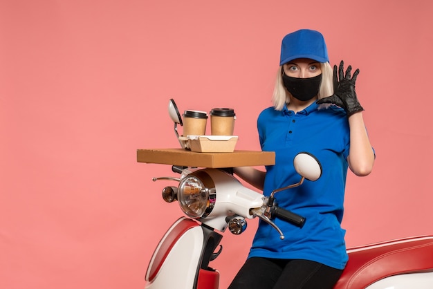 Front view female courier on bike with coffee cups on pink