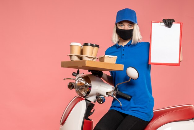 Front view female courier on bike with coffee cups on pink 