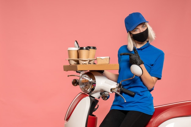 Front view female courier on bike with coffee cups on pink 