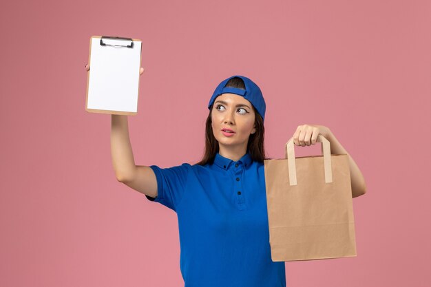 분홍색 벽에 배달 종이 패키지와 메모장을 들고 파란색 유니폼 케이프에서 전면보기 여성 택배, 직업 서비스 직원 제공