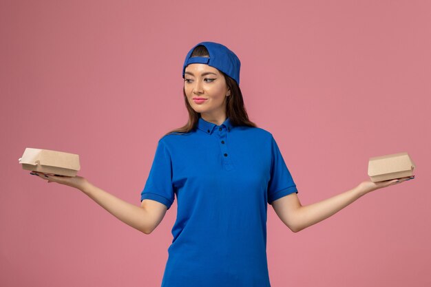 분홍색 벽, 직원 작업 서비스 배달에 작은 배달 패키지를 들고 파란색 유니폼 케이프 전면보기 여성 택배