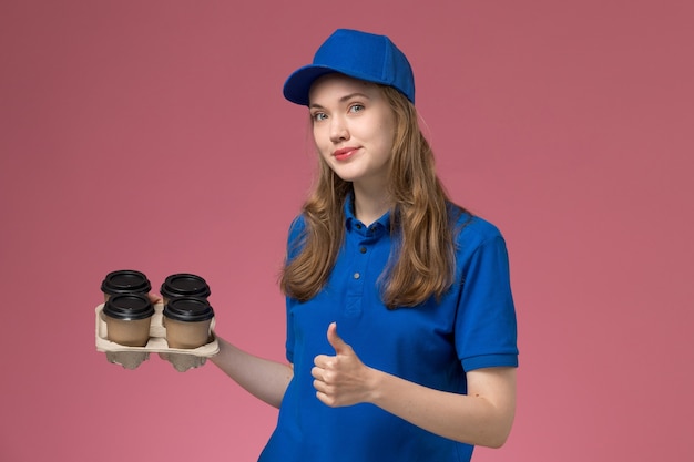 핑크 데스크 서비스 유니폼 회사 노동자에 기호처럼 보여주는 갈색 배달 커피 컵을 들고 파란색 유니폼에 전면보기 여성 택배