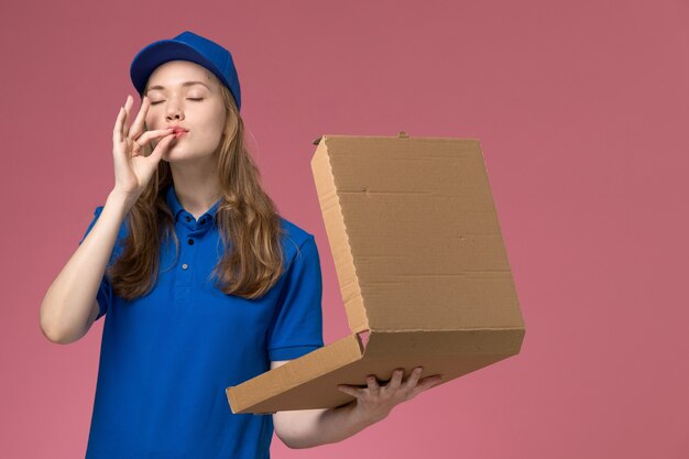 Front view female courier in blue uniform holding food delivery box on pink background worker service uniform company job