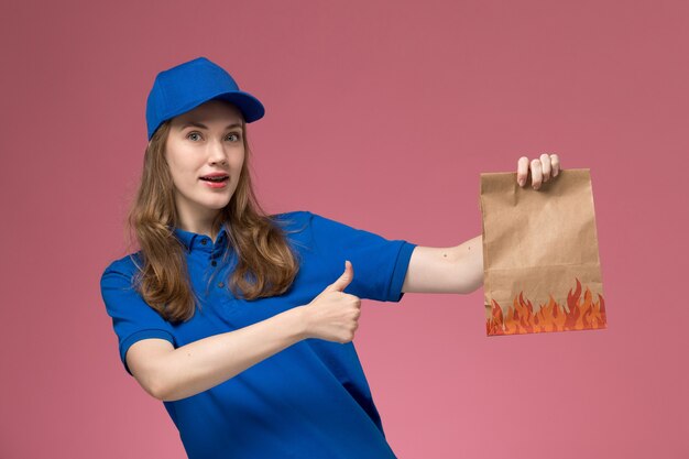 밝은 분홍색 책상 작업 노동자 서비스 유니폼 회사에 음식 패키지를 들고 파란색 유니폼에 전면보기 여성 택배