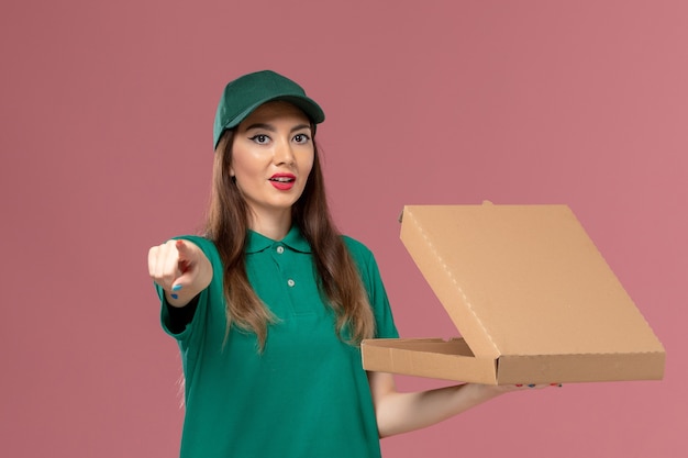 분홍색 벽 회사 서비스 유니폼 배달 작업자 작업에 음식 배달 상자를 들고 녹색 제복을 입은 전면보기 여성 택배