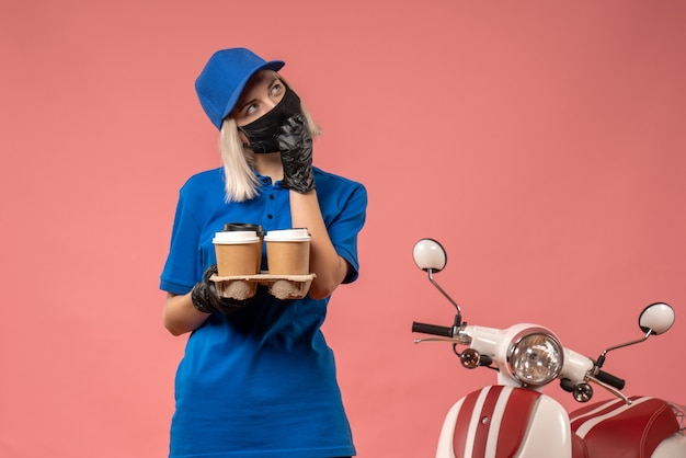 Foto gratuita corriere femminile di vista frontale che tiene le tazze di caffè sul rosa