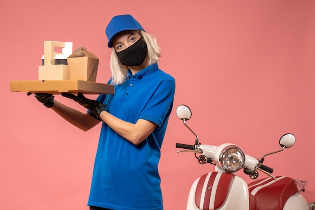 Foto gratuita corriere femminile di vista frontale che tiene le scatole dell'alimento sulla rosa