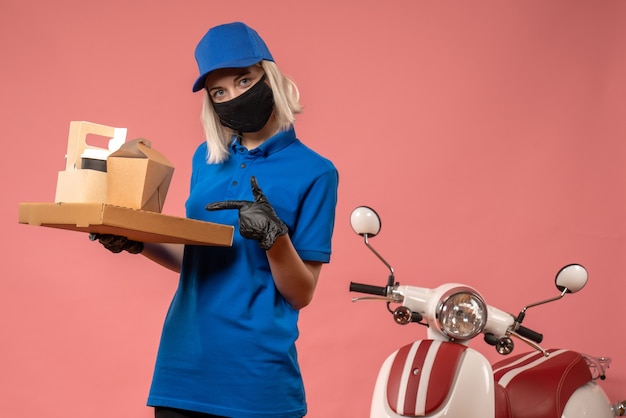 Foto gratuita corriere femminile di vista frontale che tiene le scatole dell'alimento sulla rosa