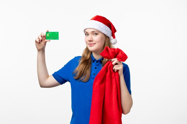 Front view of female courier holding green bank card on a white wall