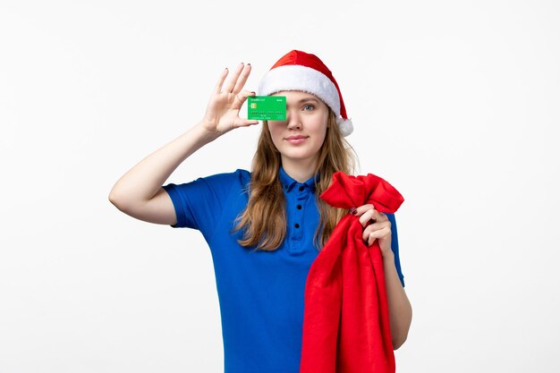 Front view of female courier holding green bank card on the white wall