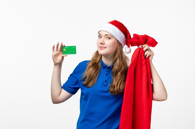 Front view of female courier holding green bank card on white wall