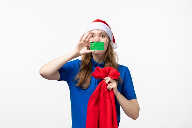 Front view of female courier holding green bank card on white wall