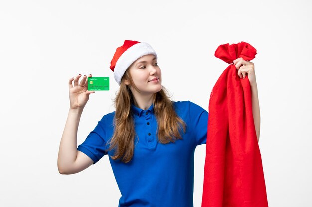 Front view of female courier holding green bank card on white wall