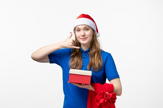 Front view of female courier holding holiday present on the white wall