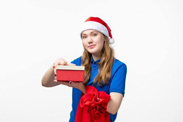 Front view of female courier holding holiday present on white wall