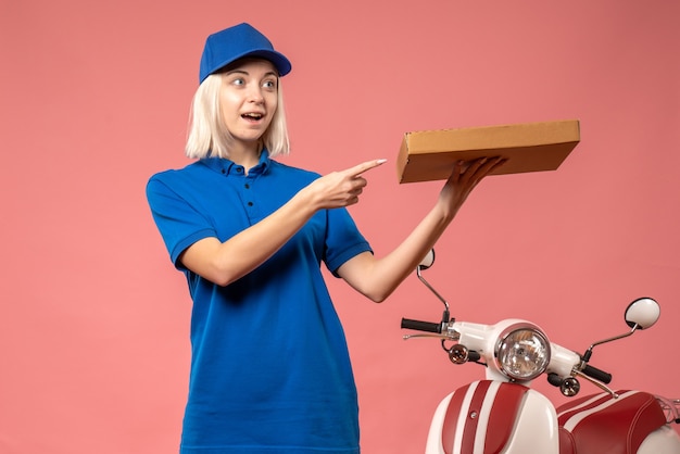 Front view female courier holding pizza box on pink 