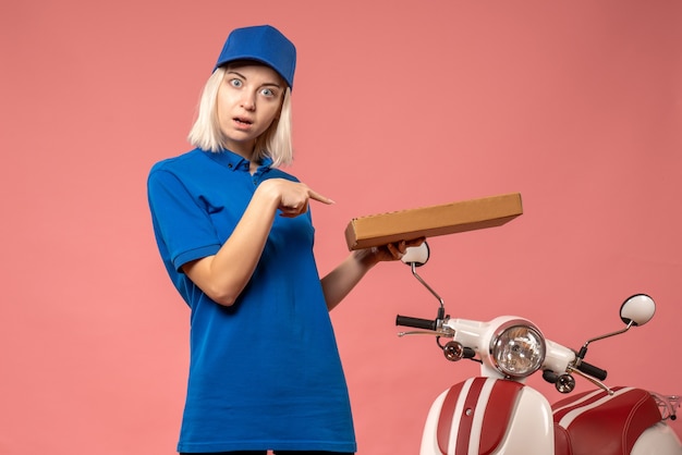 Foto gratuita corriere femminile di vista frontale che tiene la scatola della pizza sul rosa