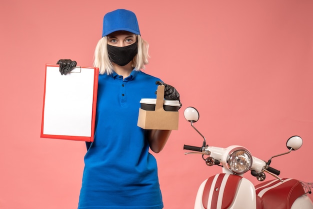 Free photo front view female courier in mask with coffee and file note on pink