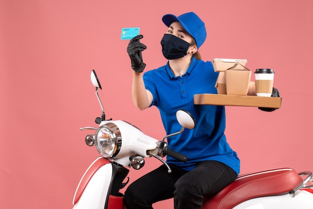 Front view female courier in mask with food delivery on pink 