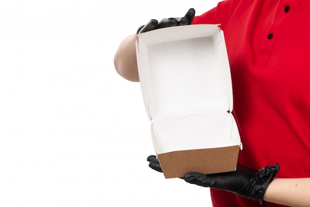 A front view female courier in red shirt and black gloves holding empty food package