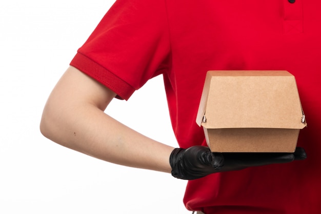 A front view female courier in red shirt and black gloves holding package with food