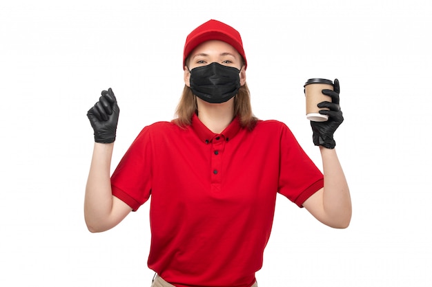 Free photo a front view female courier in red shirt red cap black gloves holding coffee on white