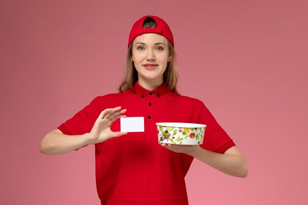 赤い制服を着た正面図の女性の宅配便と淡いピンクの壁にカード付きのケープ保持配達ボウル、労働者サービスの制服配達
