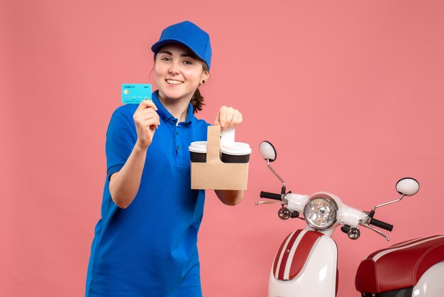 Front view female courier with coffee and bank card on pink work delivery uniform service worker pizza woman bike