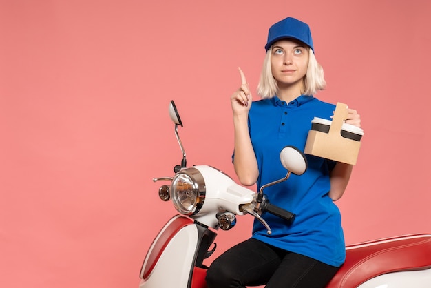 Front view female courier with coffee cups on the pink delivery service work color worker uniform job