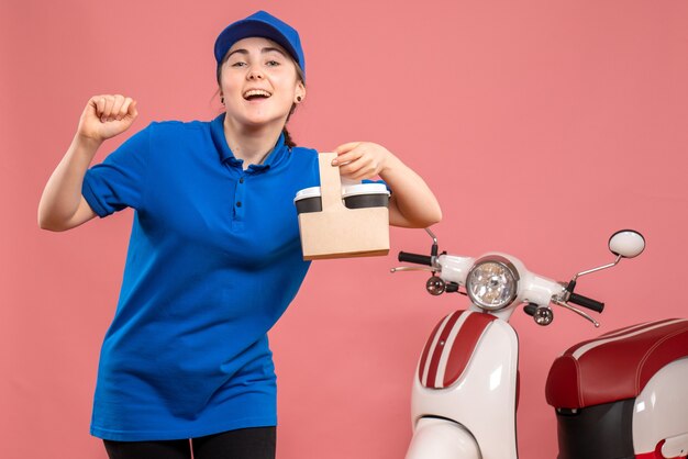 Front view female courier with delivery coffee on pink delivery service worker woman bike uniform job