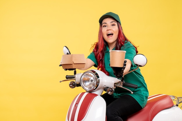 Front view of female courier with dessert on yellow wall