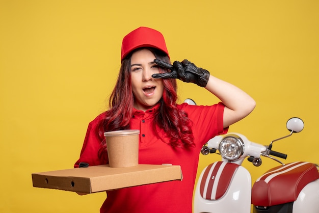 Front view of female courier with food box on yellow wall