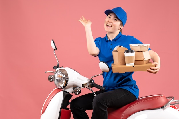 Женщина-курьер, вид спереди с пакетами еды и коробками на розовой работе, доставка еды, велосипедная униформа