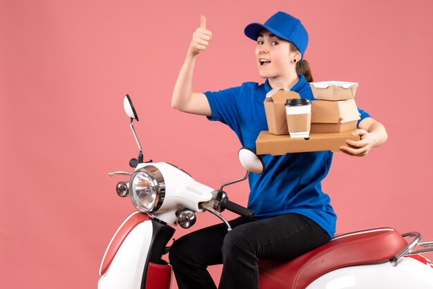 Front view female courier with food packages and boxes on pink job color worker food delivery bike service