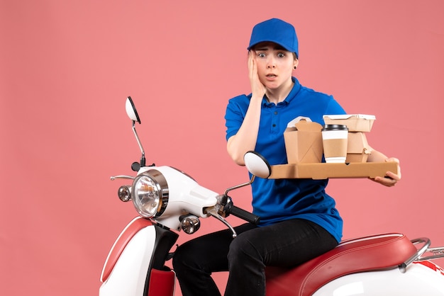 Front view female courier with food packages and boxes on pink job colors worker food delivery bike uniform service